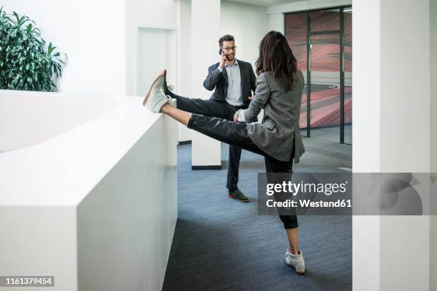 businessman and woman standing on one leg in office - office sports stock pictures, royalty-free photos & images