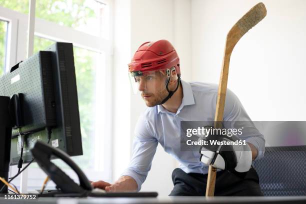 businessman dressed up as ice hockey player working at desk in office - ice hockey glove stock pictures, royalty-free photos & images