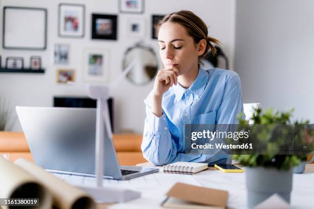 woman with closed eyes in office with wind turbine model on table - working from home stress stock pictures, royalty-free photos & images