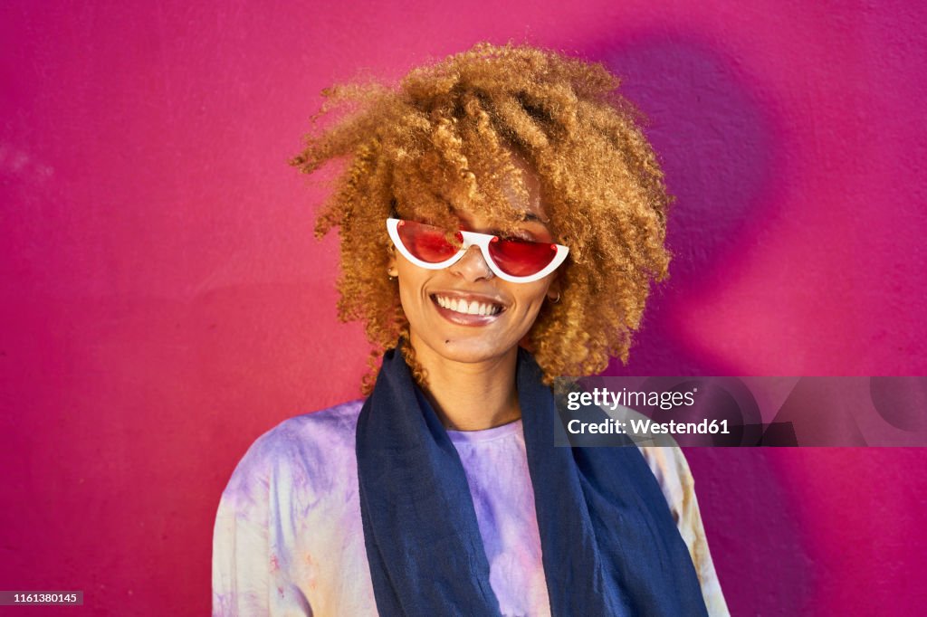 Portrait of happy woman before a pink wall