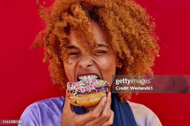 portrait of woman eating a donut - krapfen stock-fotos und bilder