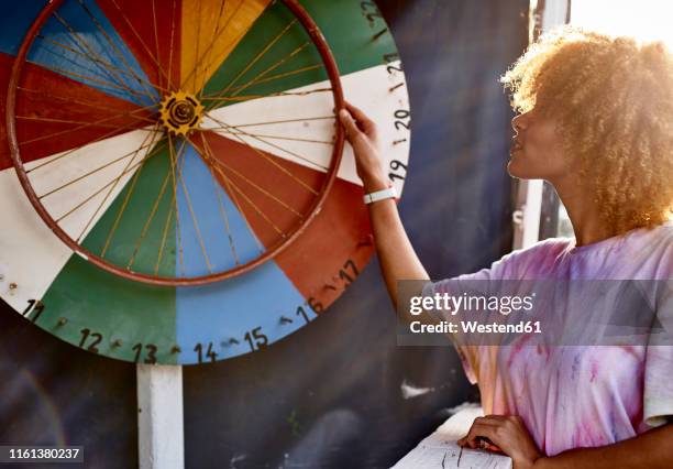 woman turning wheel of fortune - glücksrad stock-fotos und bilder