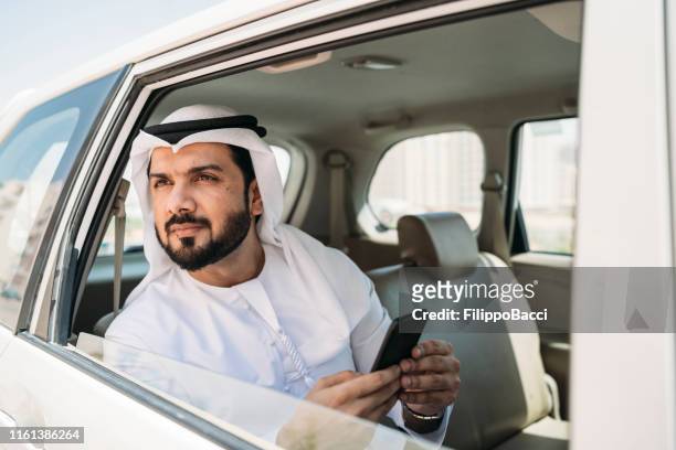 uomo d'affari arabo all'interno di un taxi in città - dubai taxi foto e immagini stock