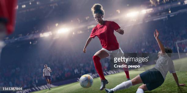 試合中にスライディングタックルを飛び越えるプロの女子サッカー選手 - 女子サッカー ストックフォトと画像