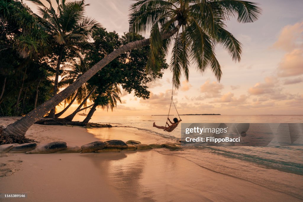 Jong volwassen vrouw ontspannen op een schommel in een tropisch paradijs