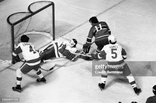 Downed goalie Jimmy Rutherford of the Red Wings looks for the puck after making a save on Canadien Yvon Lambert in the first period of the...