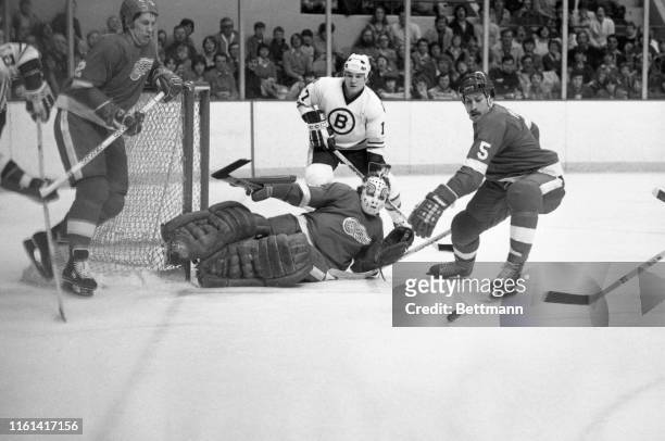 Detroit goalie Jim Rutherford falls to the ice to deflect puck as Bruins' Stan Jonathan moves in behind him during 2nd period of game at Boston...