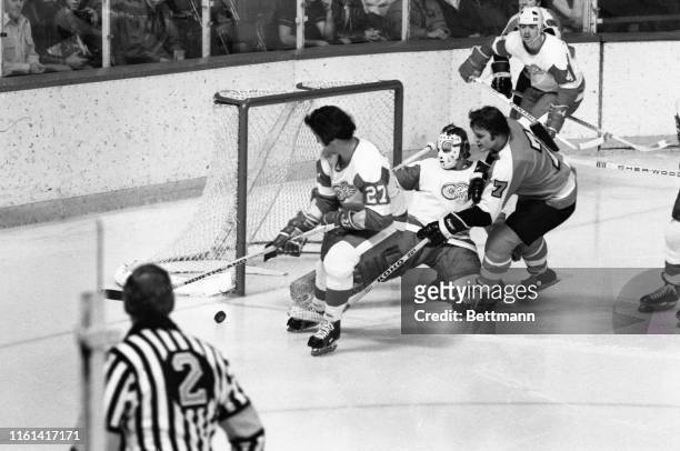 Red Wings' goalie Jim Rutherford kicks aside Flyers' Bill Barber's shot during the 1st period of the Detroit-Philadelphia game. Waiting to pick up...