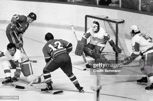 Red Wings' goalie Jim Rutherford stops Canadiens' Jacques Lamaire's shot with his stick as red Wings' defense man Bryan Watson ties up Canadiens'...