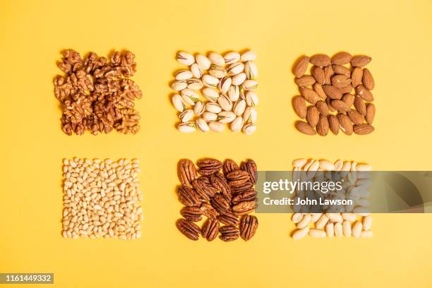 nuts on a yellow background - pekannuss stock-fotos und bilder