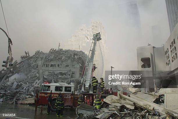 New York City firefighters work at the World Trade Center after two hijacked planes crashed into the Twin Towers September 11, 2001 in New York.