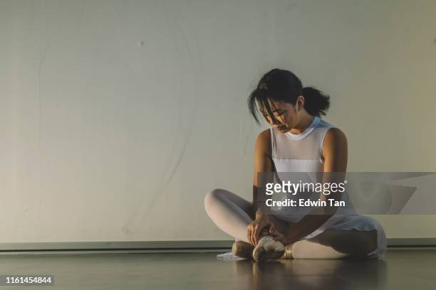 een aziatische chinese vrouwelijke tiener pijn haar been tijdens de praktijk in haar ballet studio en zitten op de vloer met pijn - gymnastic asian stockfoto's en -beelden
