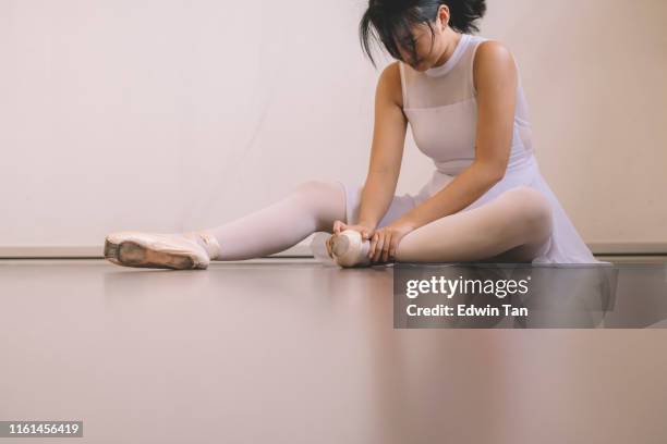 an asian chinese female teenager hurt her leg during practise in her ballet studio and sit on the floor with pain - ballet feet hurt stock pictures, royalty-free photos & images