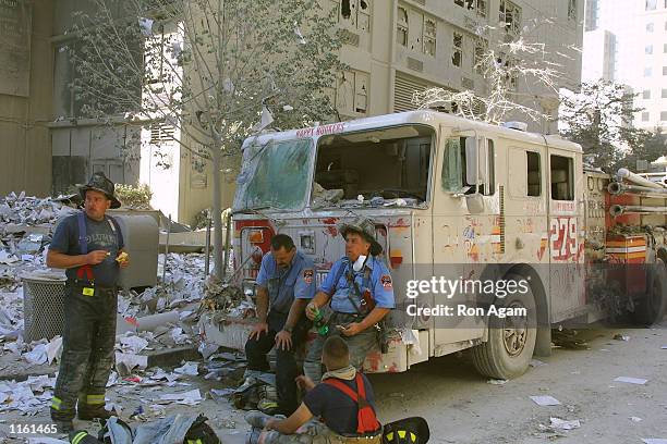 New York City firefighters take a rest at the World Trade Center after two hijacked planes crashed into the Twin Towers September 11, 2001 in New...