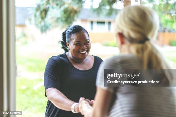 adult african american female e caucasica davanti alla porta di residenza salutarsi con una stretta di mano - vicino foto e immagini stock