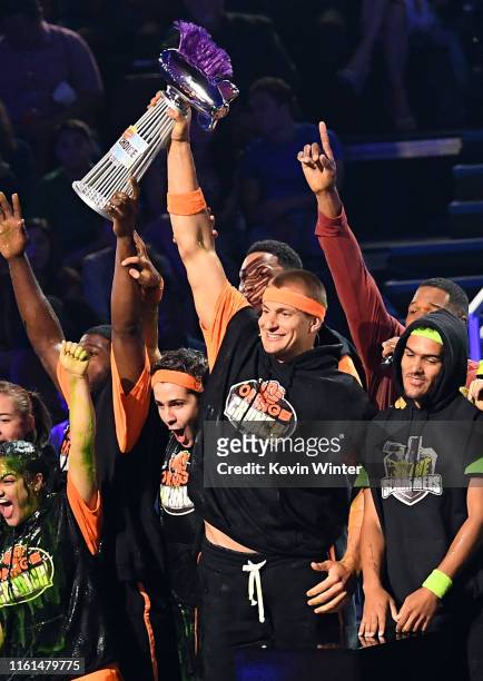 Laurie Hernandez, P. K. Subban, David Dobrik, Rob Gronkowski accept a trophy after winning a challenge while Trae Young looks on onstage during...
