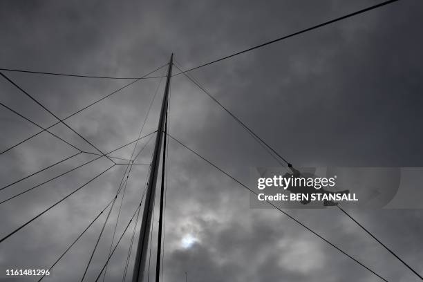 Member of the crew climbs the rigging of the Malizia II sailing yacht at the Mayflower Marina in Plymouth, southwest England, on August 13, 2019...