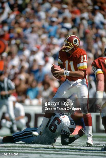 Mark Rypien of the Washington Redskins looks to pass under pressure from Ken Harvey of the Phoenix Cardinals during an NFL football game September...