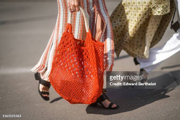 Guest wears a white and red striped and fringed skirt, a woven red shopping bag, black sandals, outside Acne, during Paris Fashion Week - Haute...