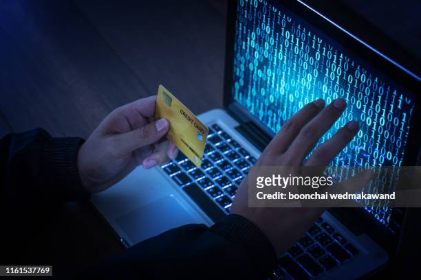 hands of anonymous hackers holding credit card - fraud photos et images de collection