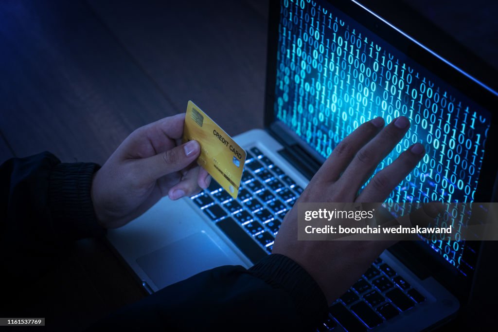 Hands of anonymous hackers holding credit card