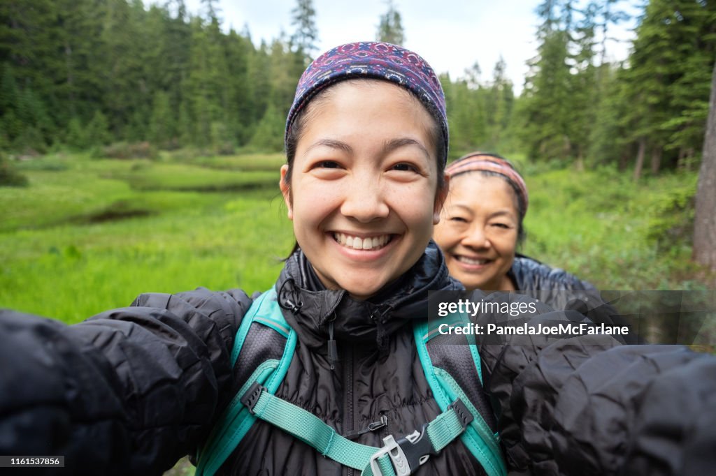 Filha e matriz que tomam o Selfie ao caminhar ao longo do Lago alpino