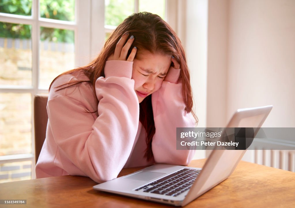 Teenager crying using laptop