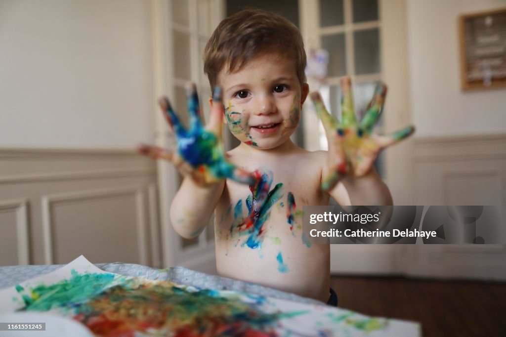 A 2 years old boy doing painting at home