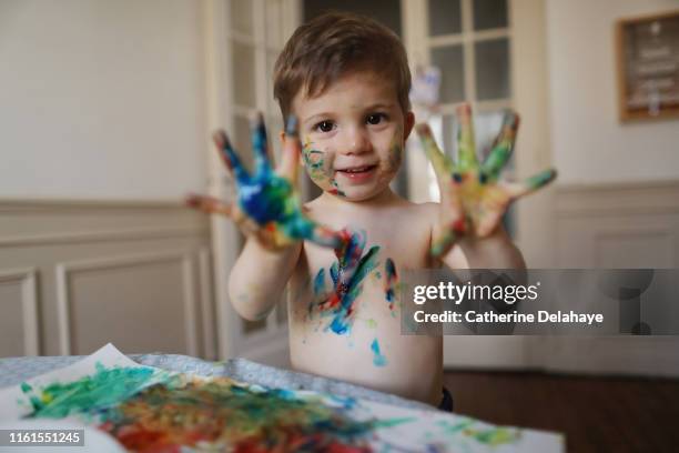 a 2 years old boy doing painting at home - manos pintadas fotografías e imágenes de stock