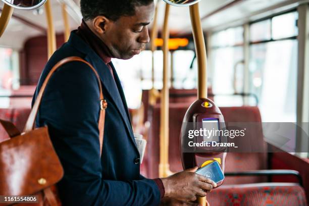 mature commuter in london using contactless payment for the fare - london bus stock pictures, royalty-free photos & images