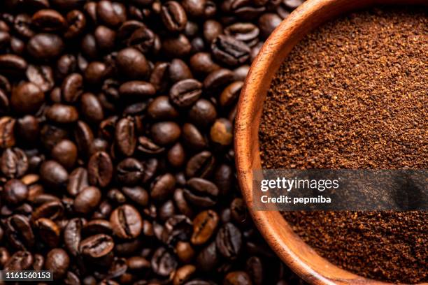 ground coffee in bowl over coffee beans background - ground coffee stock pictures, royalty-free photos & images