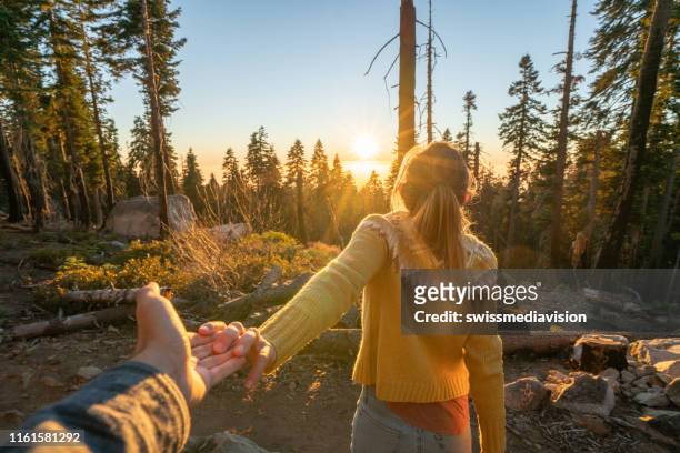 follow me to concept; young woman leading boyfriend to forest in autumn - follow through stock pictures, royalty-free photos & images