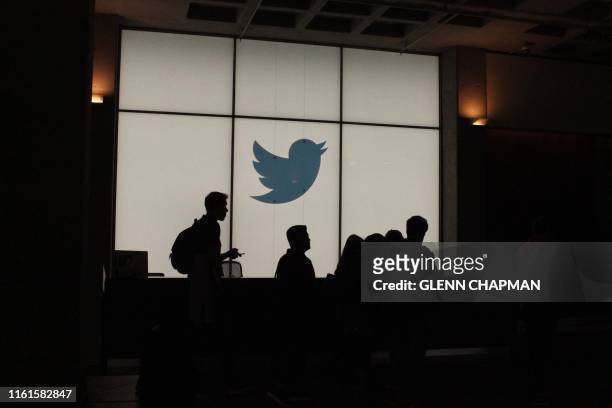 Employees walk past a lighted Twitter log as they leave the company's headquarters in San Francisco on August 13, 2019. - Twitter on August 13 said...