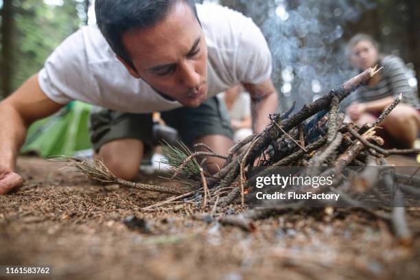 homme de camping faisant un feu de camp - survivor photos et images de collection