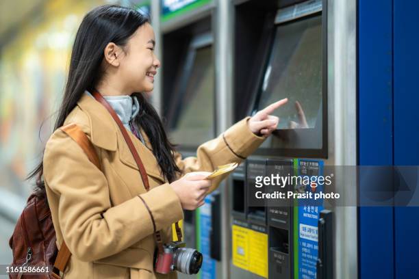 asian woman tourist buying at automated ticketing machines on the subway in seoul, south korea. - korean teen - fotografias e filmes do acervo