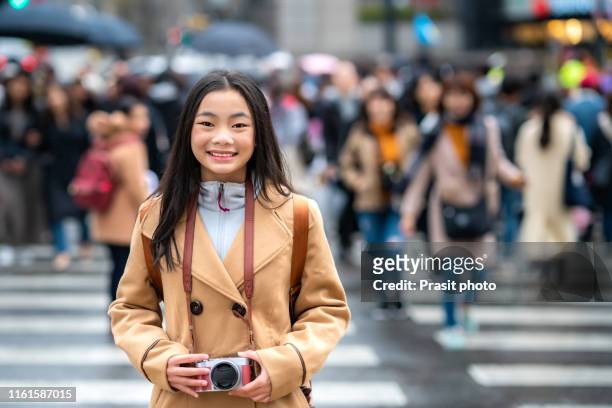 traveler asian woman with camera standing and smiling at the crosswalk in the city of seoul. south korea. - korean teen bildbanksfoton och bilder