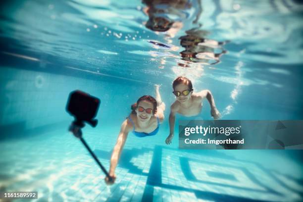 two happy kids filming themselves with underwater camera - go pro camera stock pictures, royalty-free photos & images