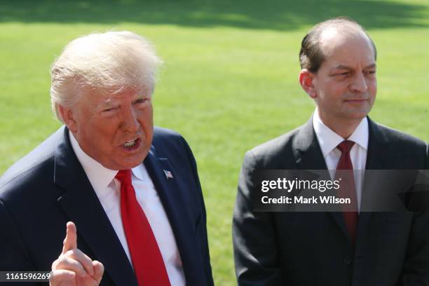 President Donald Trump stands with Labor Secretary Alex Acosta, who announced his resignation, while talking to the media at the White House on July...