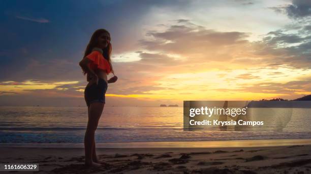 beautiful young woman at twilight in a tropical beach in costa rica - girl beach sunset stock-fotos und bilder