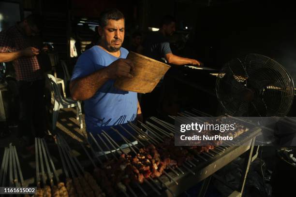 Man grills kebab skewers in the open air outside a restaurant in Gaza City on August 13 as people celebrate during the third day of the Muslim...
