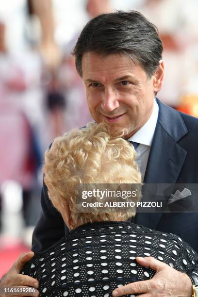 Italy's Prime Minister Giuseppe Conte embraces a victim's relative prior to a mass for the first anniversary of the collapse of the Morandi bridge,...