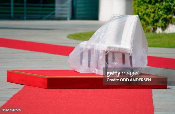 Two chairs under a protective cover stand on a podium and a red carpet as preparations are under way for a welcoming ceremony for Lithuania's...