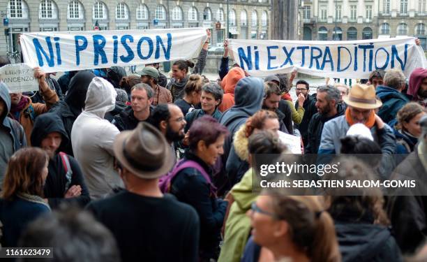 People hold banners reading "Neither prison Neither extradition" during a gathering in support of Vincenzo Vecchi outside Rennes' courthouse, on...