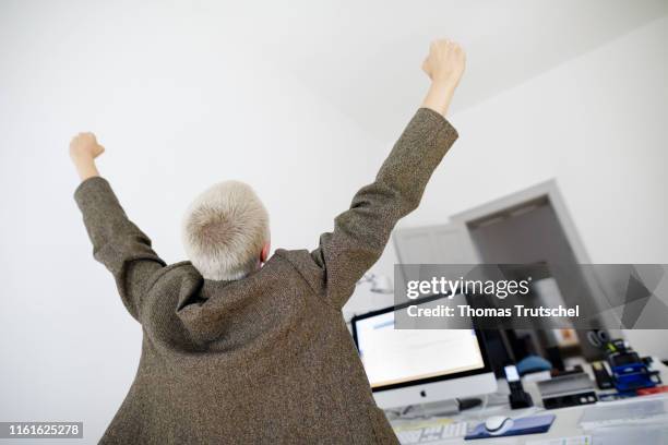 Berlin, Germany Symbolic photo on the topic of Success in the office: A woman sits at the desk and pulls her hands upwards on August 14, 2019 in...