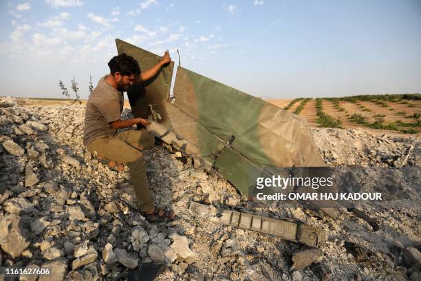 Rebel fighter stands near the remains of a downed regime warplane near the jihadist-held town of Khan Sheikhun in the south of Idlib province on...