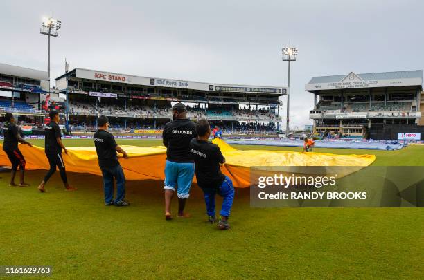 Ground staff pull off the rain covers during the 3rd ODI match between West Indies and India at Queens Park Oval, Port of Spain, Trinidad and Tobago,...