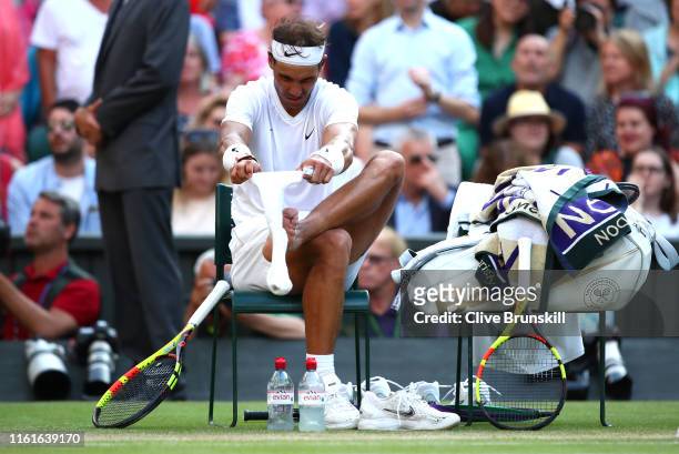 Rafael Nadal of Spain changes his socks during a change of serve in his Men's Singles semi-final match against Roger Federer of Switzerland during...