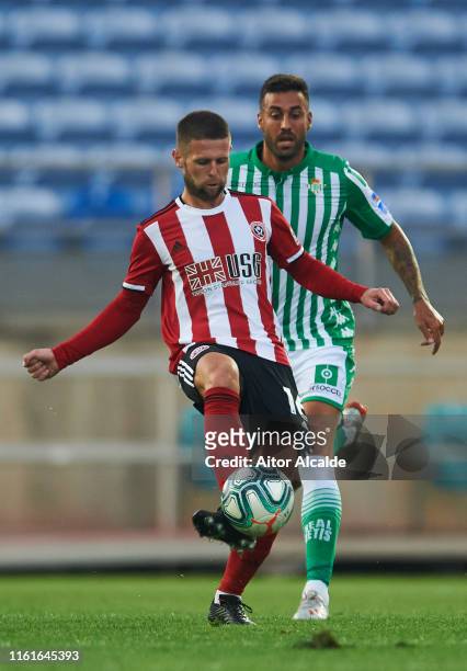 Victor Camarasa of Real Betis Balompie duels for the ball with Ollie Norwood of Sheffield United during a pre-season friendly match between Real...