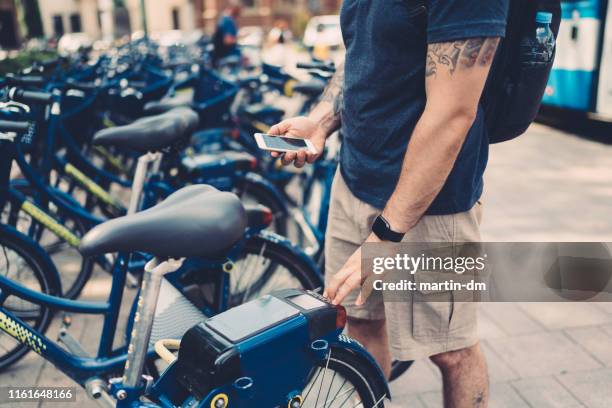 toerist in krakau huurfiets via mobiele app - bicycle rental stockfoto's en -beelden