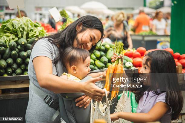 madre con niños comprando en el mercado - mercado de productos de granja fotografías e imágenes de stock